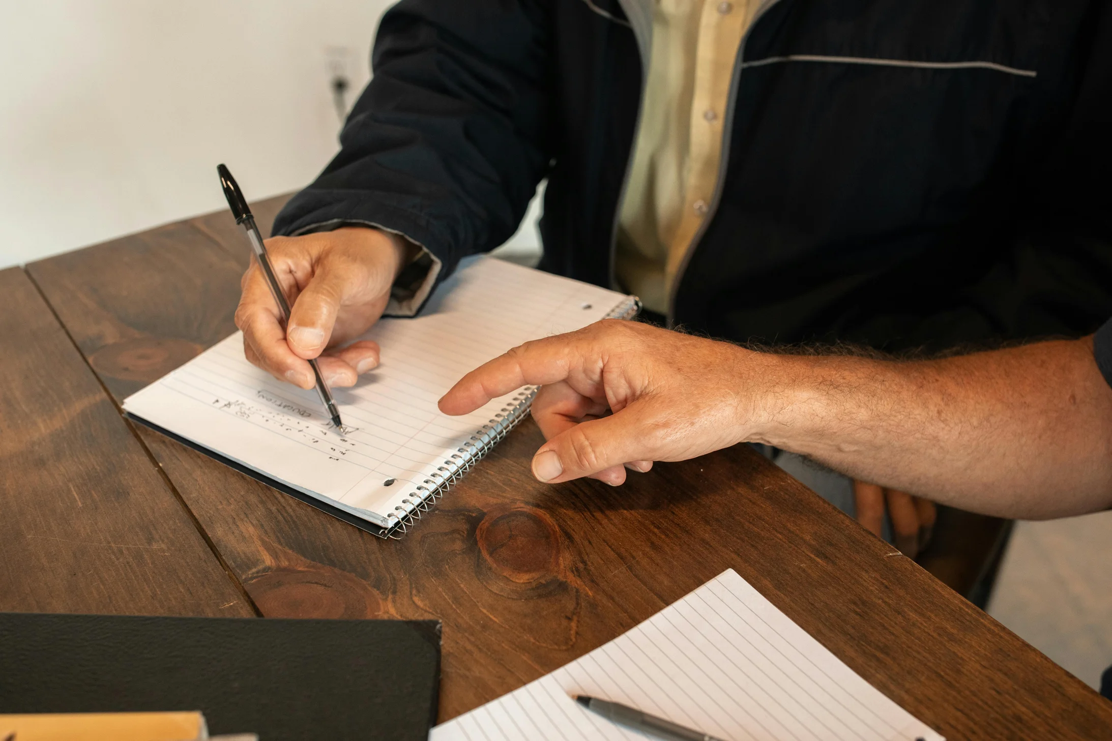 Two adults collaborating on notes in a writing workshop setting.