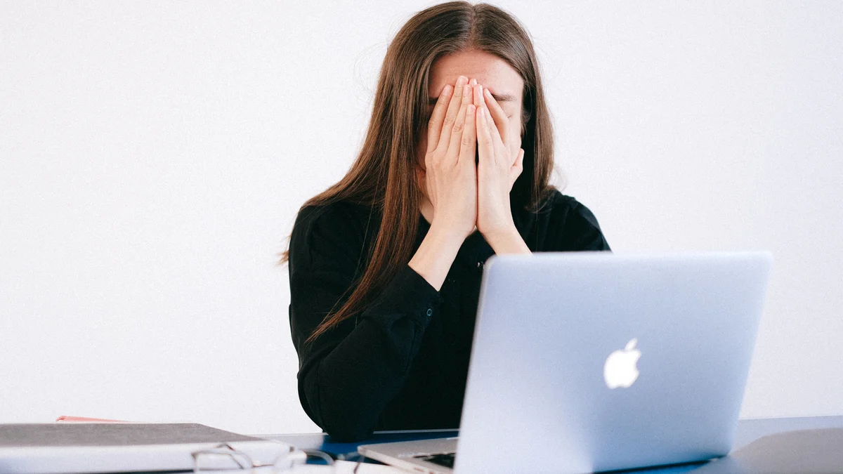 Woman with hands on her face in front of a laptop