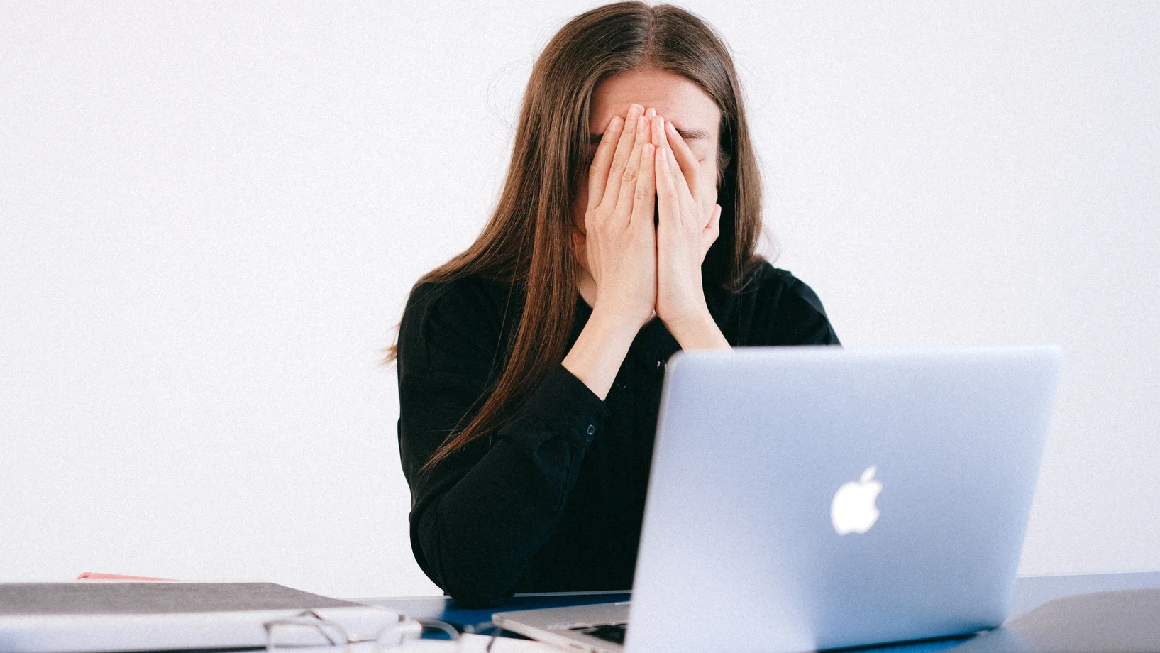 Woman with hands on her face in front of a laptop