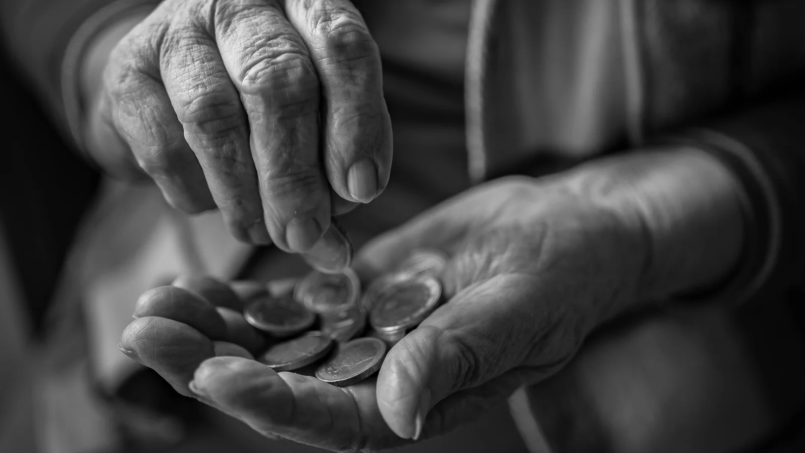 An old woman is holding a coin in her hand