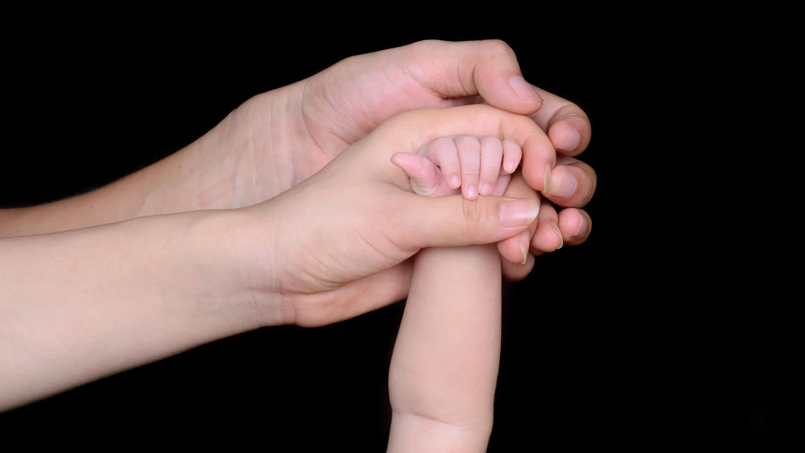 A close-up image featuring a baby's hand being held by a parent's hand, symbolizing love and protection.
