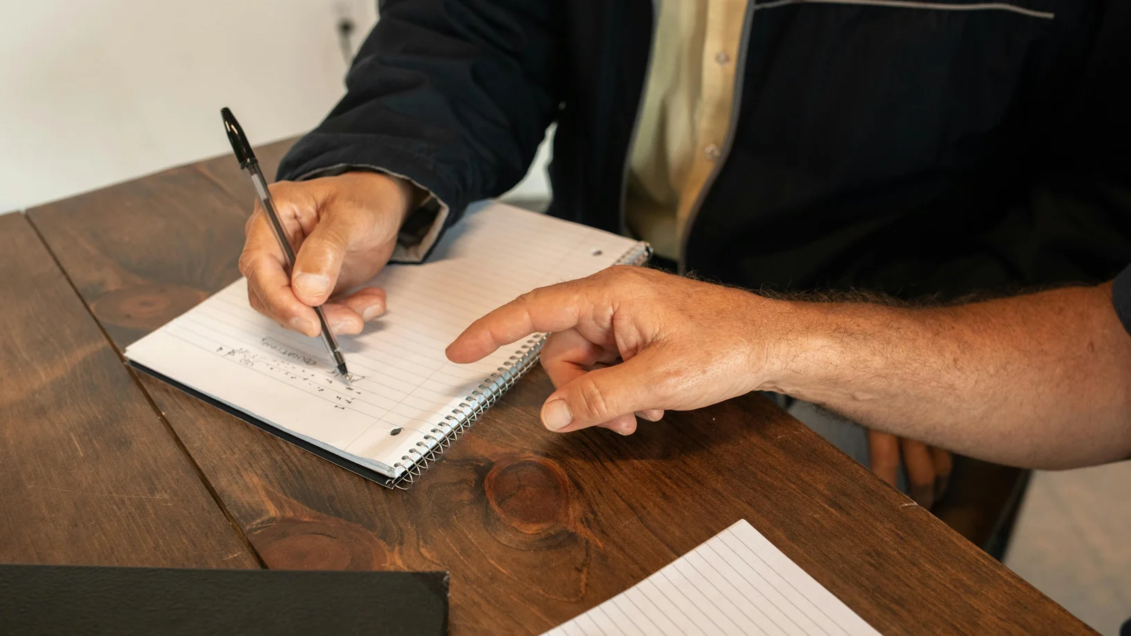 Two adults collaborating on notes in a writing workshop setting.
